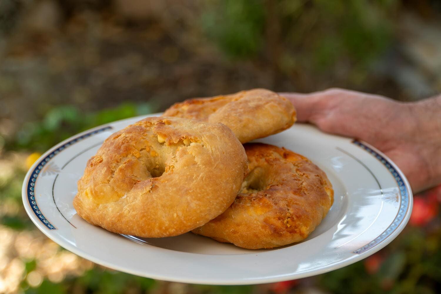 Hand holding a plate with large baked biscuits – A plate with traditional Thessaloniki biscuits held by hand, showcasing the city’s rich culinary heritage.
