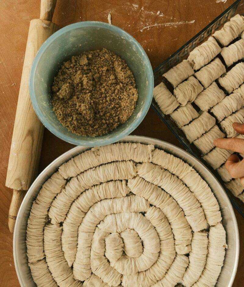 Traditional preparation of baklava during an immersive cooking workshop, with dough spirals and a bowl of ground nuts on a wooden table
