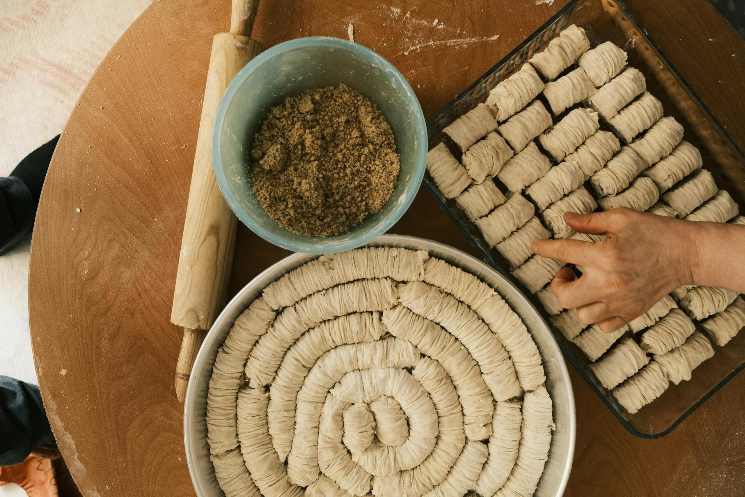 Traditional preparation of baklava during an immersive cooking workshop, with dough spirals and a bowl of ground nuts on a wooden table