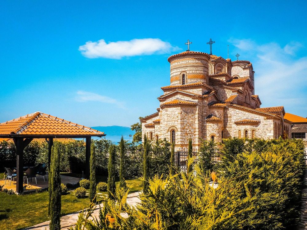 A picturesque church by Ohrid Lake, nestled in the stunning natural landscape of North Macedonia, reflecting the spiritual depth of religion in the Balkans.