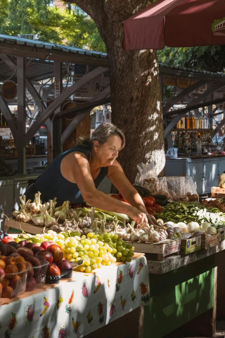 Local market visit on our Istria culinary tour: a woman selling fresh vegetables, grapes, and nectarines, highlighting the region’s vibrant produce.
