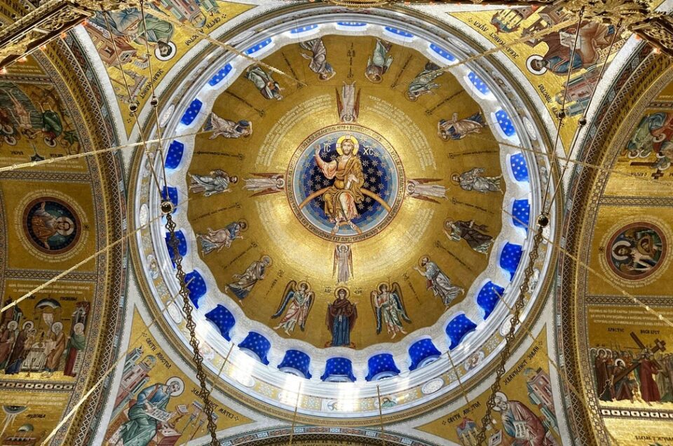Golden painting of Christ Pantokrator on the ceiling of an Eastern Orthodox Church, showcasing intricate Byzantine artistry.